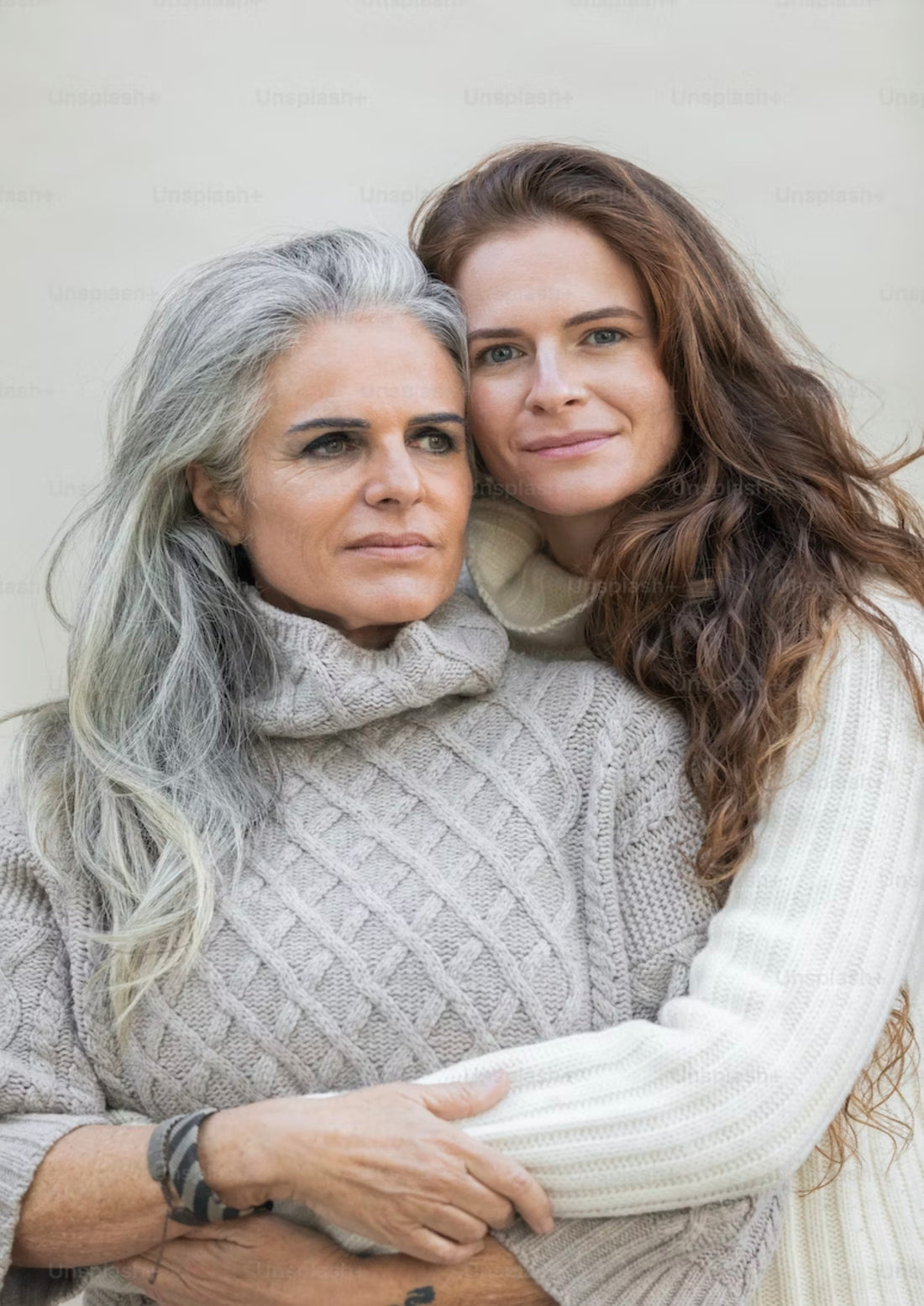 A woman with dark brown hair is in bracing a woman with silver grey hair